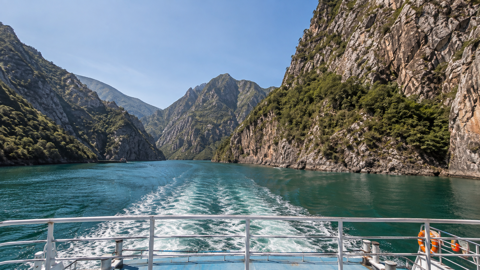 Lake Koman winding through narrow green mountain canyons