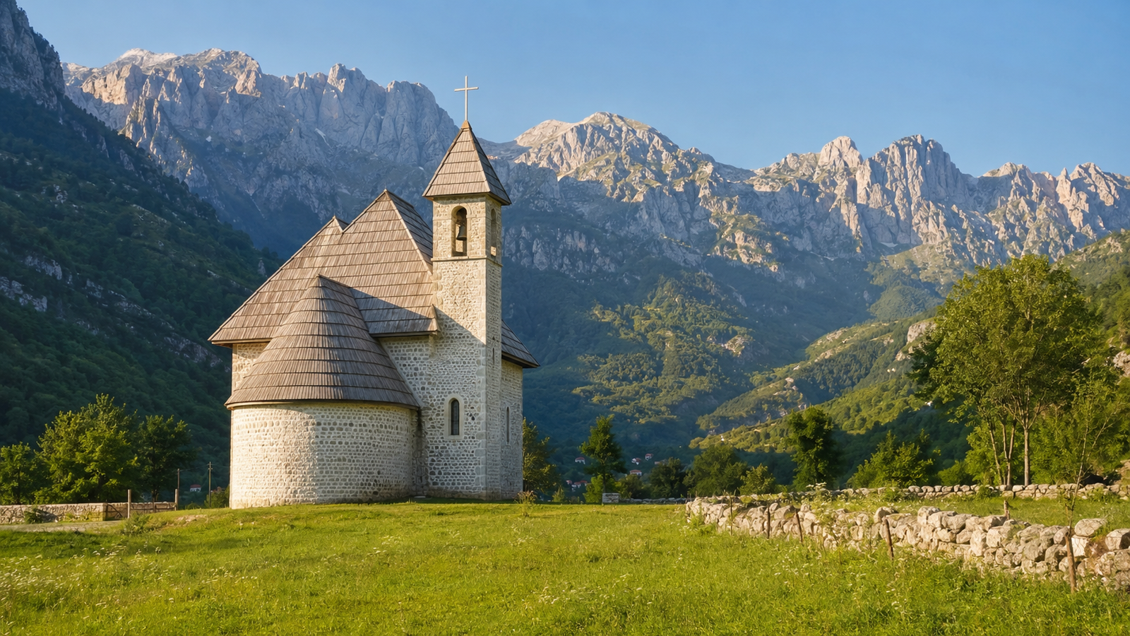 Theth Church in a green meadow beneath the Albanian Alps