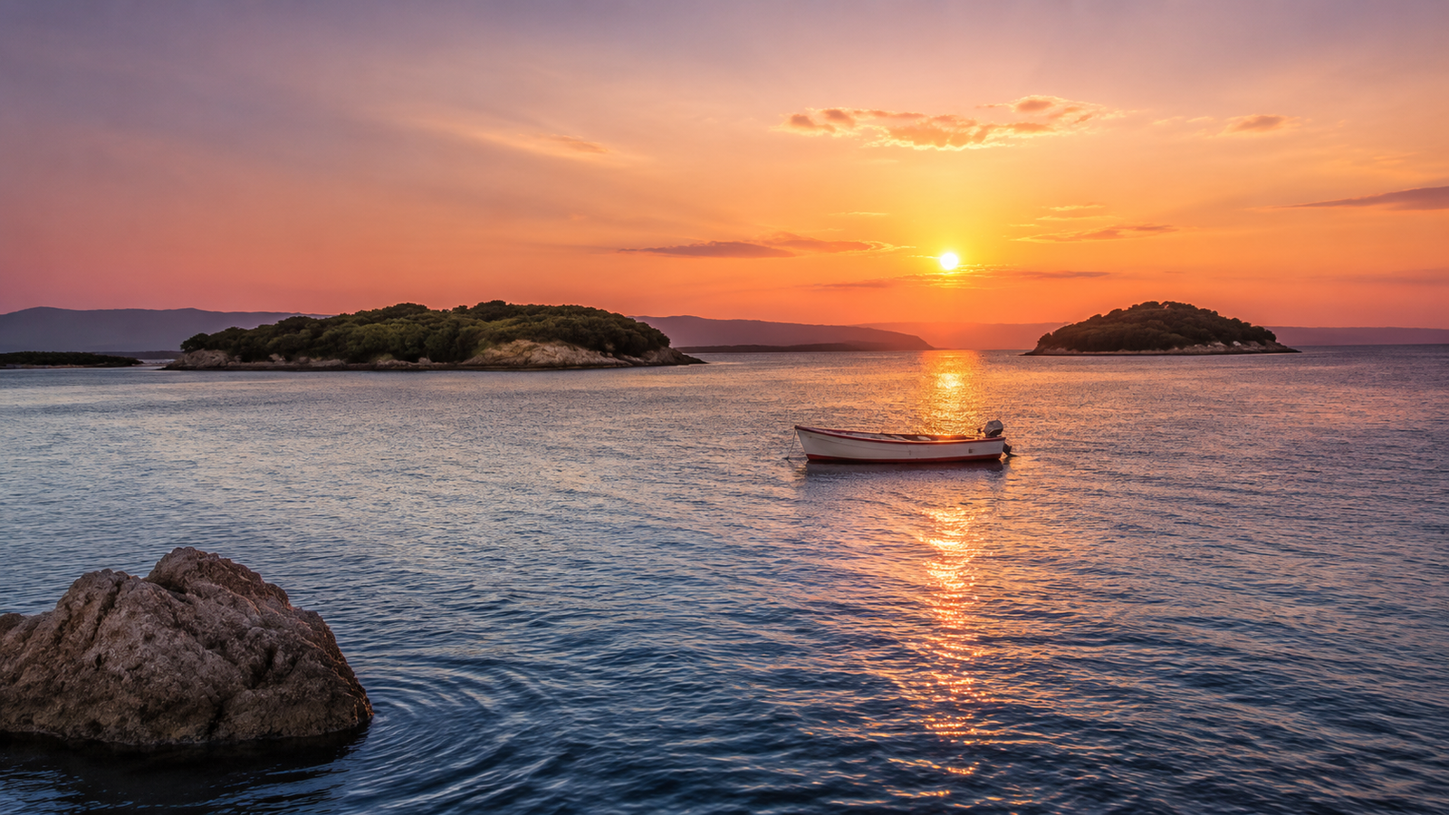 Sunset over the Ksamil Islands with a small boat on calm water